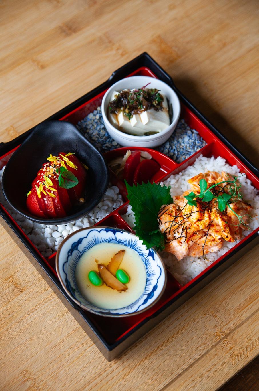 Traditional Japanese bento box with various dishes on a wooden surface