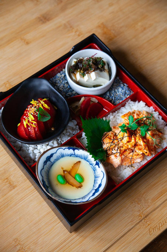 Traditional Japanese bento box with various dishes on a wooden surface