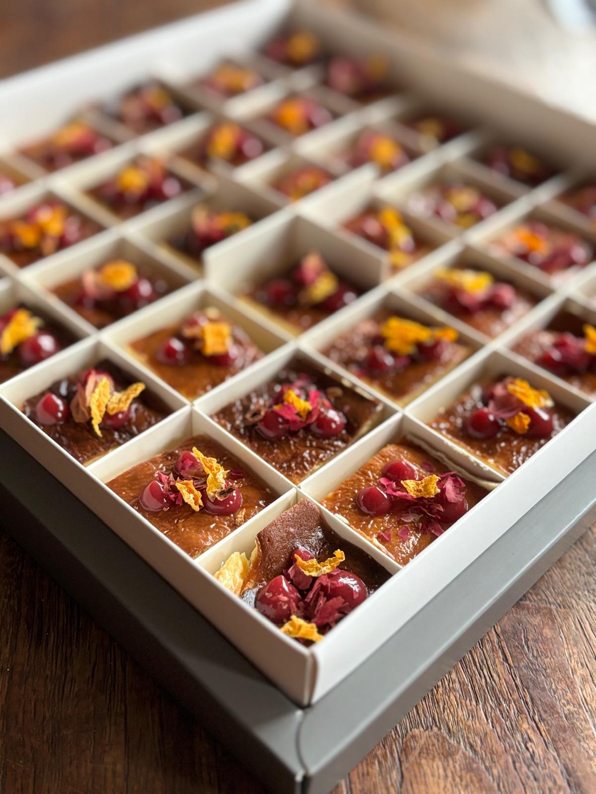 Box of small desserts with dried fruits and flowers on a wooden surface