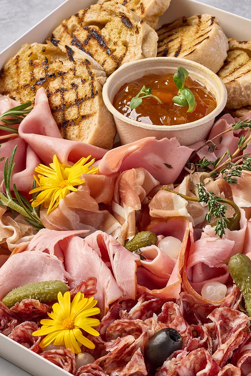 Platter of cured meats and bread with a small bowl of dip.