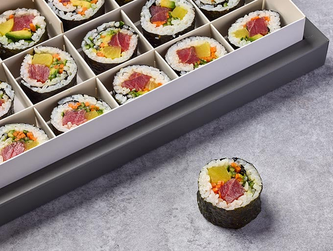 Sushi rolls in a compartmentalized tray on a gray surface