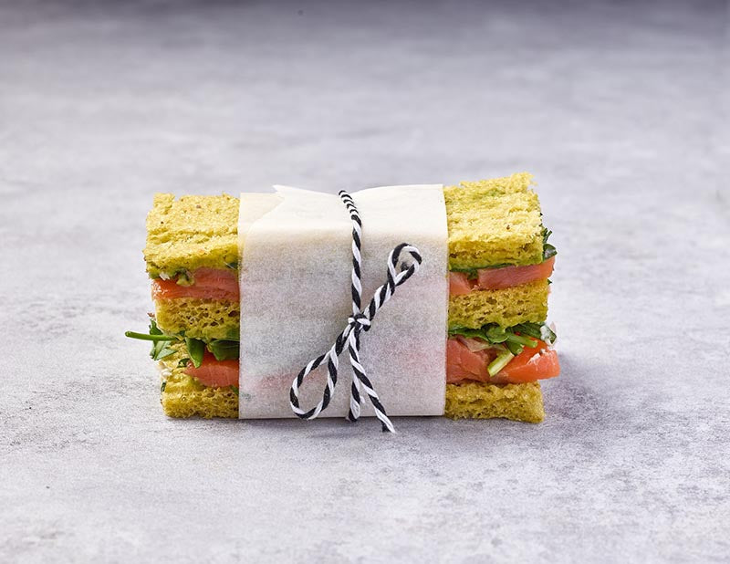 A sandwiche wrapped in paper with a string on a gray surface