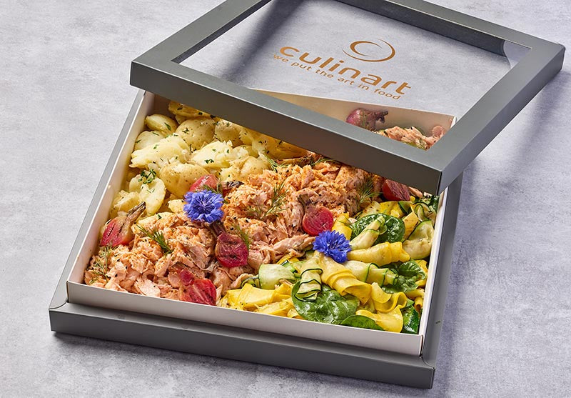Flaked salmon dish with vegetables in a box with 'culinart' branding on a gray background