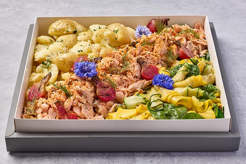 Flaked salmon in a box with colorful flowers on a gray background