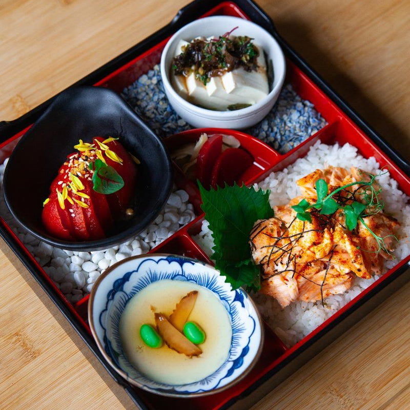 Traditional Japanese bento box with various dishes on a wooden surface