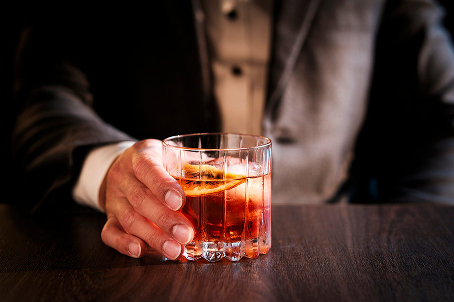 A glass of Negroni with an orange slice on a wooden surface